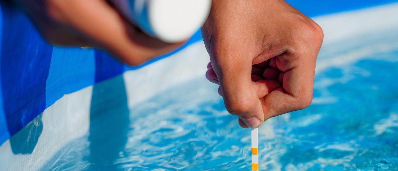 Checking the water quality of a pool with the help of a test strip with PH value, chlorine and algaecide. High quality photo